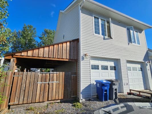 Two-story house with garage and bins.