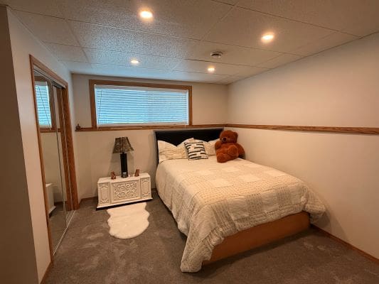 Cozy bedroom with bed and teddy bear.