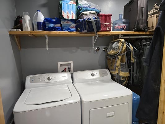 Laundry room with washer, dryer, and shelves.