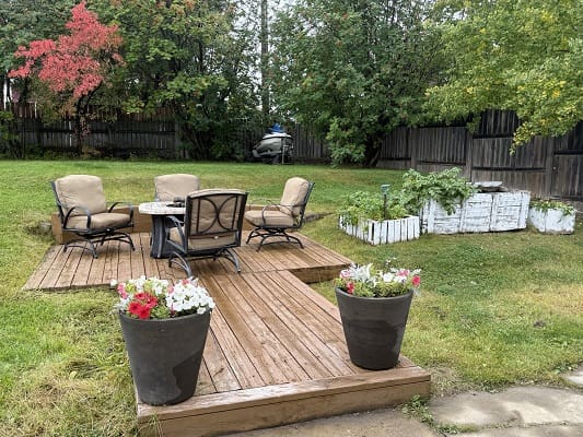 Backyard patio with chairs and potted flowers.