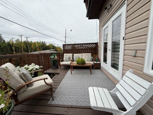 Wooden patio with chairs and potted plants.