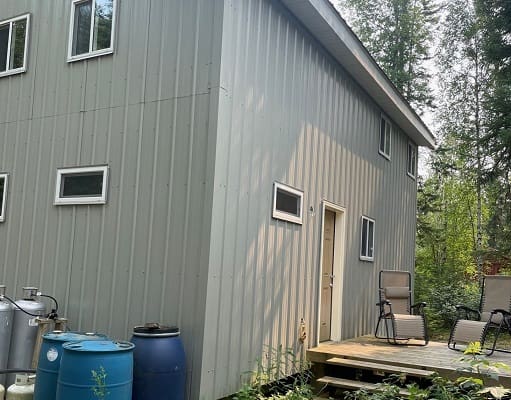Metal building with chairs on wooden deck.