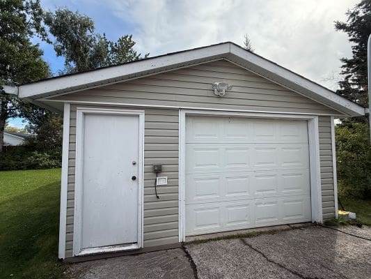 Small garage with white door and siding.