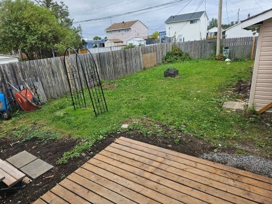 Backyard with grass and wooden deck.