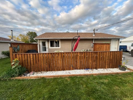 House with wooden fence and cloudy sky.