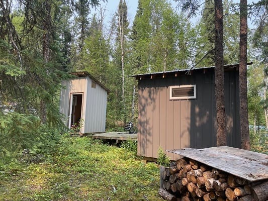Wooden sheds in a forested area.