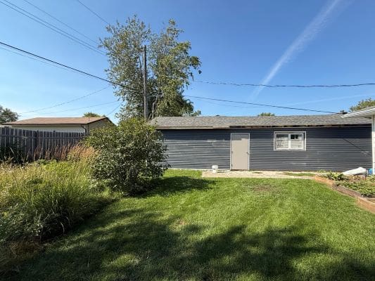 Backyard with grass, garage, and trees.