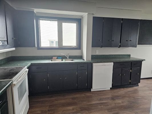 Dark kitchen with green countertops and window.