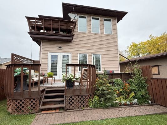 Two-story house with wooden deck and garden.