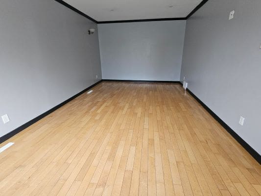 Empty room with wooden floor and gray walls.
