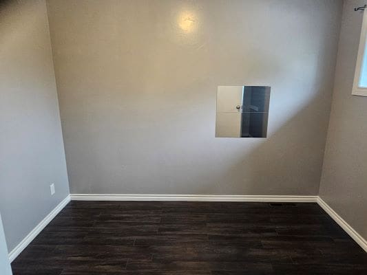 Empty room with hardwood floor and hatch.
