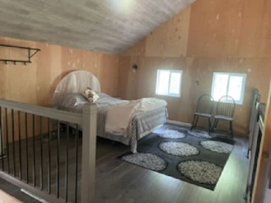 Cozy loft bedroom with bed and chairs.