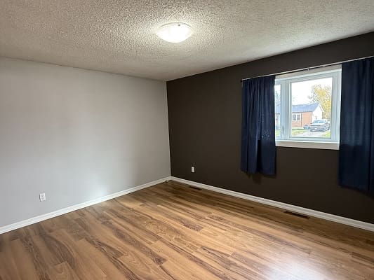 Empty room with wood floor and window.