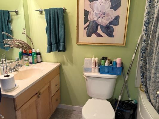 Bathroom with green walls and floral painting.