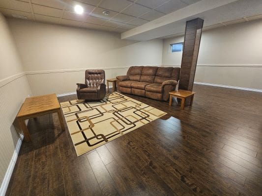 Basement with sofa, armchair, and tables.