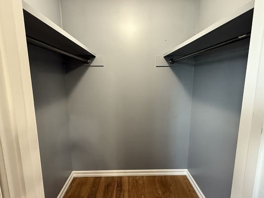 Empty walk-in closet with wooden floor.