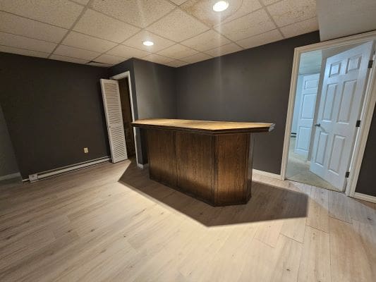 Home bar in basement with wood flooring.
