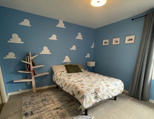 Bedroom with cloud wall and tree bookshelf.