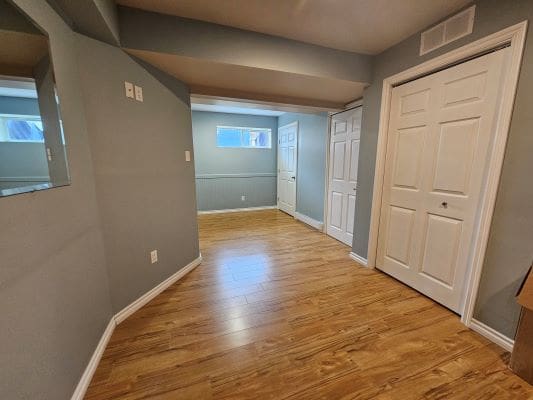 Basement room with wooden floor and closets.