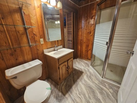 Wood-paneled bathroom with shower and vanity.