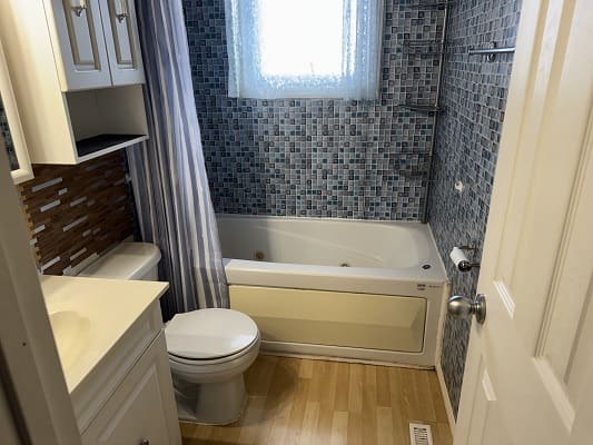 Small bathroom with bathtub and mosaic tiles.