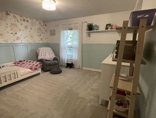 Child's bedroom with floral wallpaper and toys.