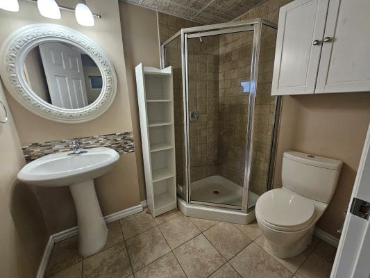 Modern bathroom with shower and pedestal sink.