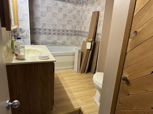 Small bathroom with wooden decor and bathtub.