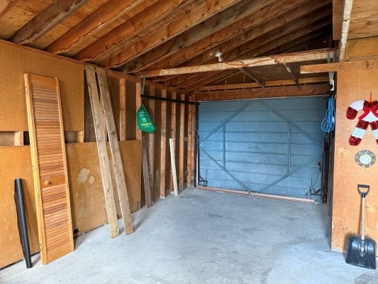 Empty garage with wooden beams and shelves.