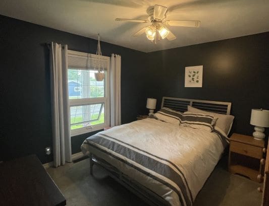 Cozy bedroom with dark walls and bed.