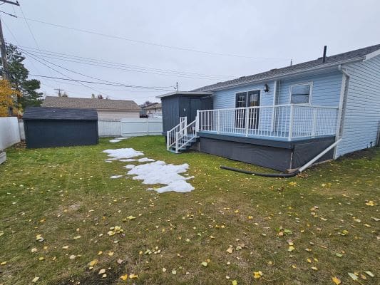 Backyard with deck and melting snow patches.