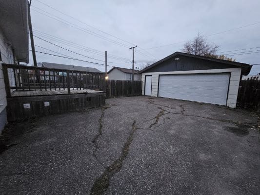 Concrete driveway with garage and wooden deck.