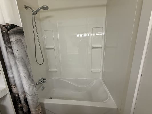 White bathtub with shower curtain and head.