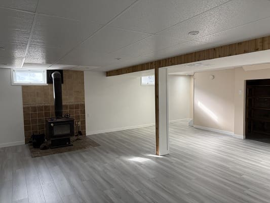 Spacious basement with wood stove and beams.