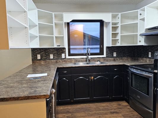 Kitchen with empty white cabinets and appliances.
