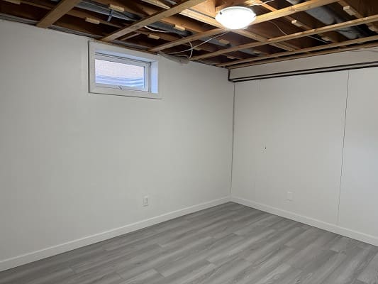 Unfinished basement room with exposed ceiling beams.