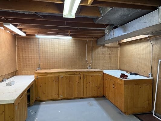 Basement workshop with wooden cabinets and lights.