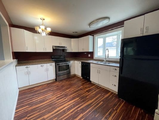 Modern kitchen with wooden floor and appliances.