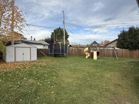 Backyard with shed, trampoline, and slide.