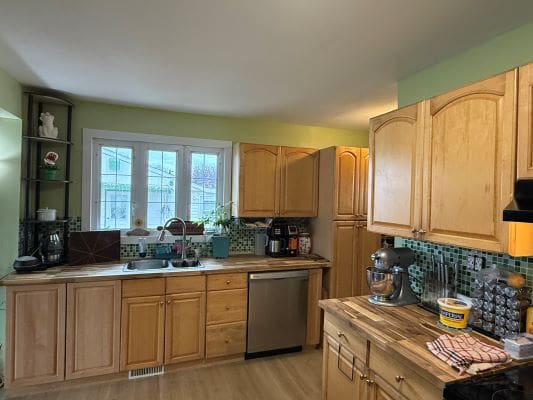 Wooden kitchen with green walls and window.