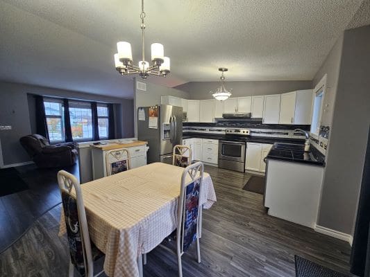 Modern kitchen and dining area with chandelier.