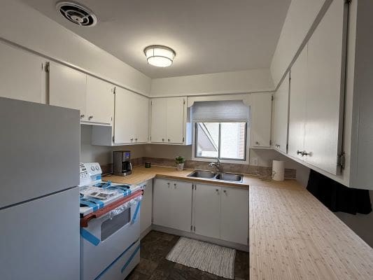 Small kitchen with white cabinets and appliances.