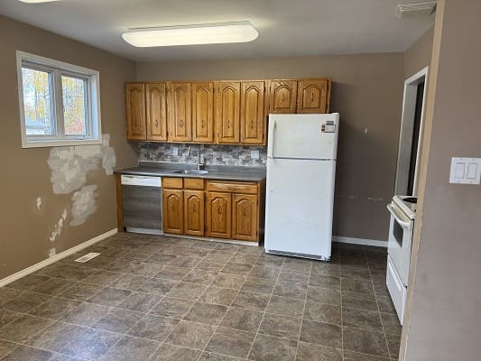 Empty kitchen with wooden cabinets and appliances.