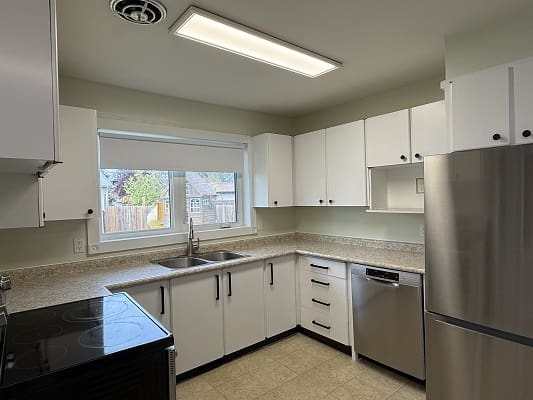 Modern kitchen with white cabinets and appliances.