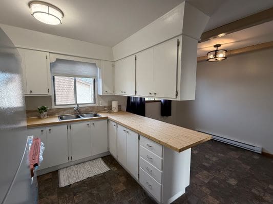 White kitchen with wooden countertops and window.