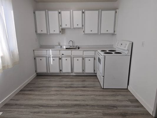 Small kitchen with white cabinets and stove.