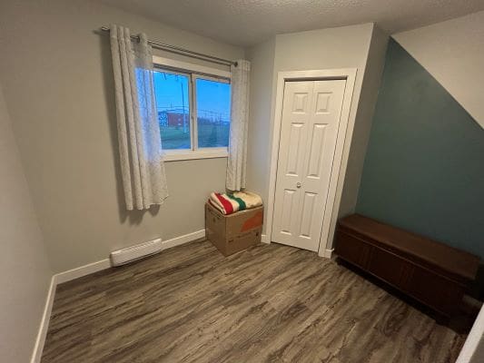 Small room with window and wooden floor.