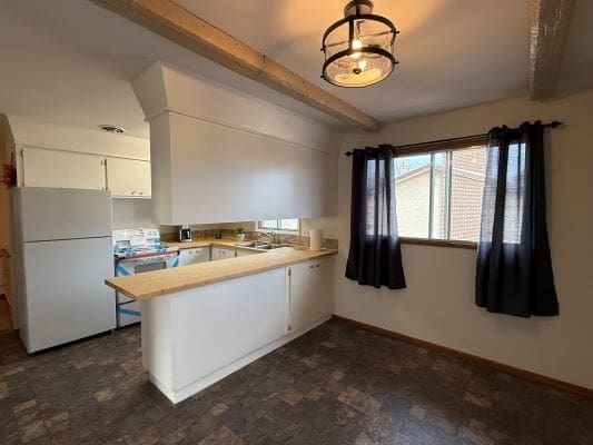 Cozy kitchen with dark curtains and fridge.