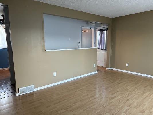 Empty room with wooden floor and beige walls.