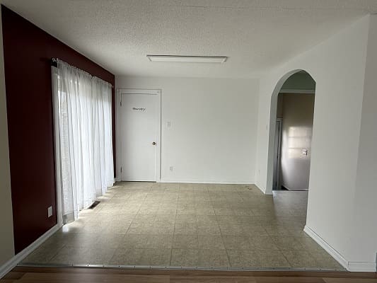 Empty room with tiled floor and curtains.